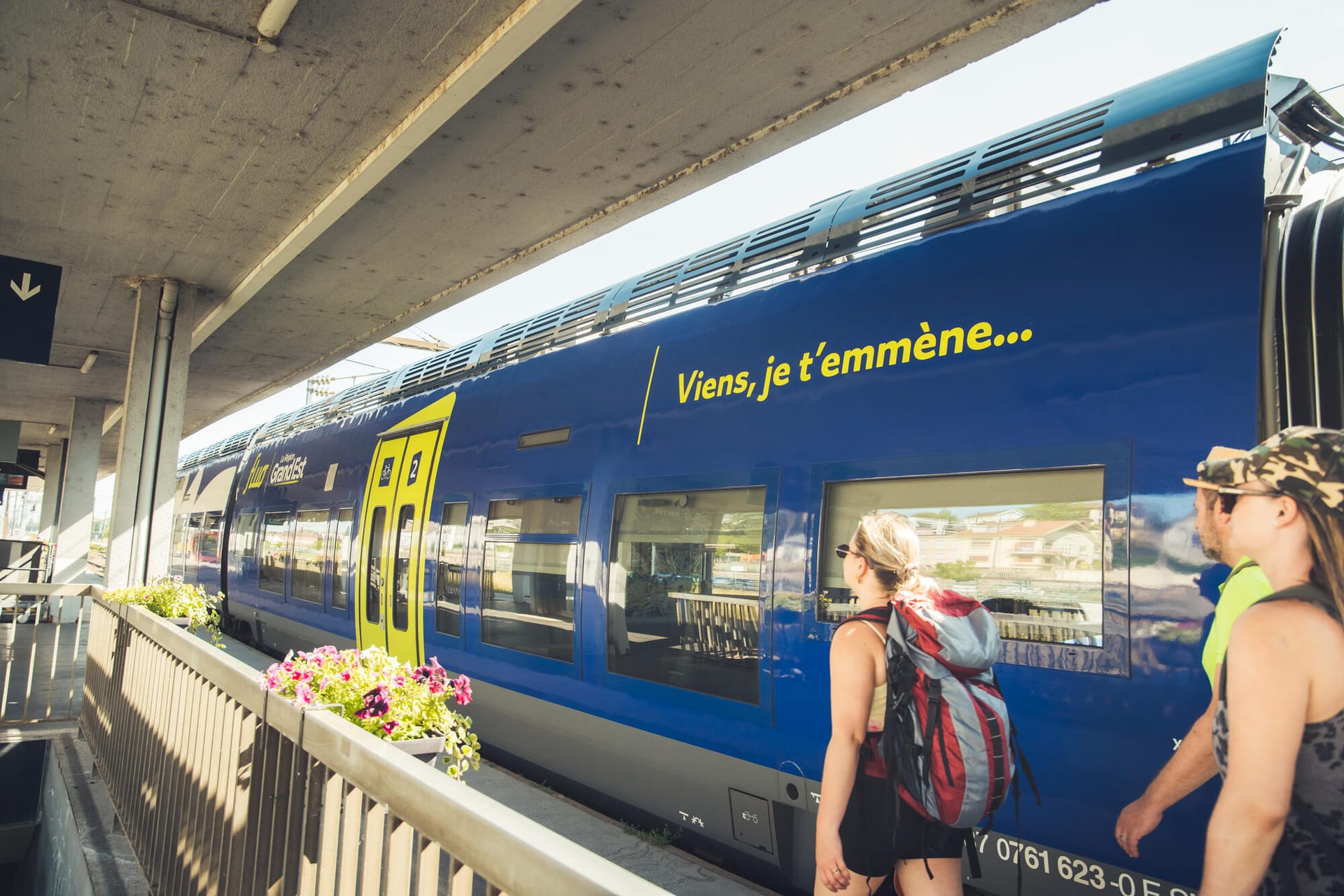 Voyageurs sur un quai devant un train TER Grand Est à l'arrêt en gare